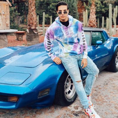 Vadhir Derbez posing with his car for a photo shoot.